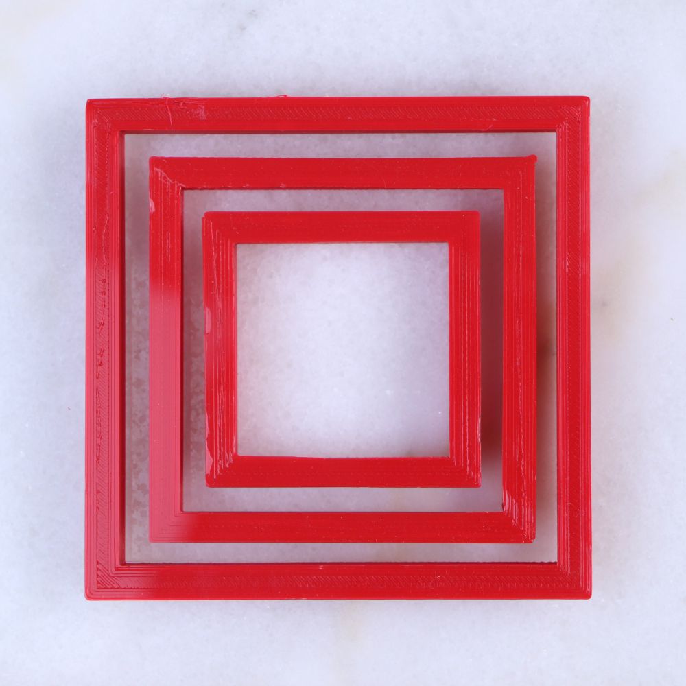 Nested square cookie cutter set in red, featuring three graduated sizes: 2", 3", and 4", ideal for baking and crafting stencils.