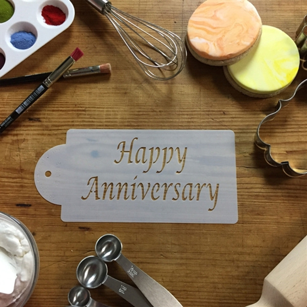 Happy Anniversary cake stencil on a wooden table with various baking tools and colored icing.