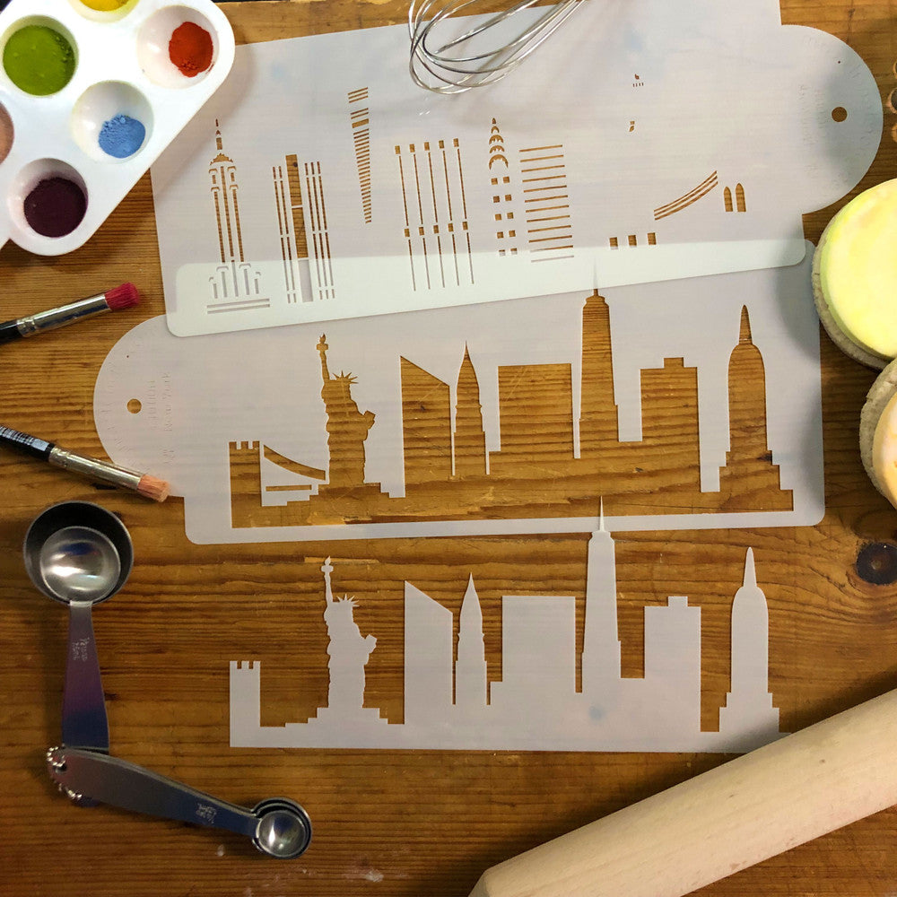New York City skyline cake stencil side showcasing iconic landmarks on wooden surface with painting tools.