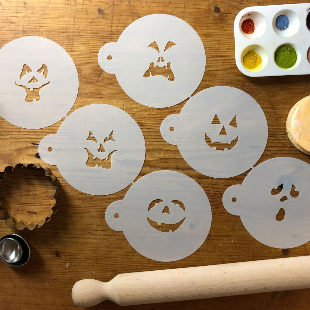 Jack-O-Lantern Halloween faces cookie stencil set on a wooden table with baking tools and paint palette.