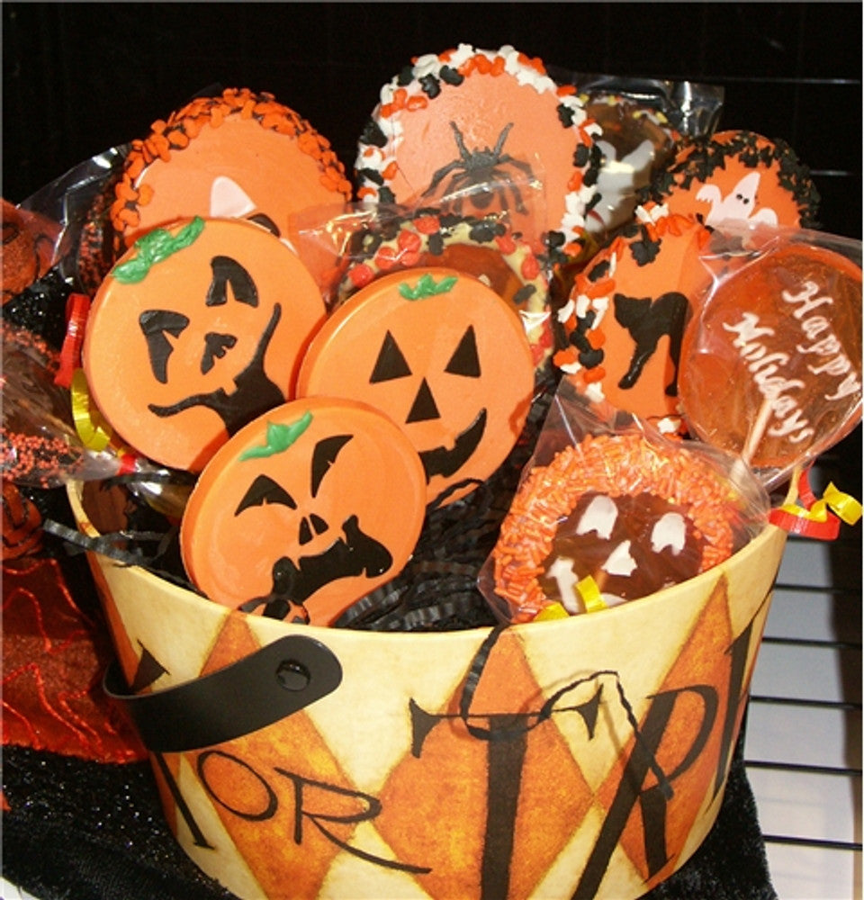 Colorful Halloween-themed cookies in a decorative basket featuring pumpkin faces and festive designs.
