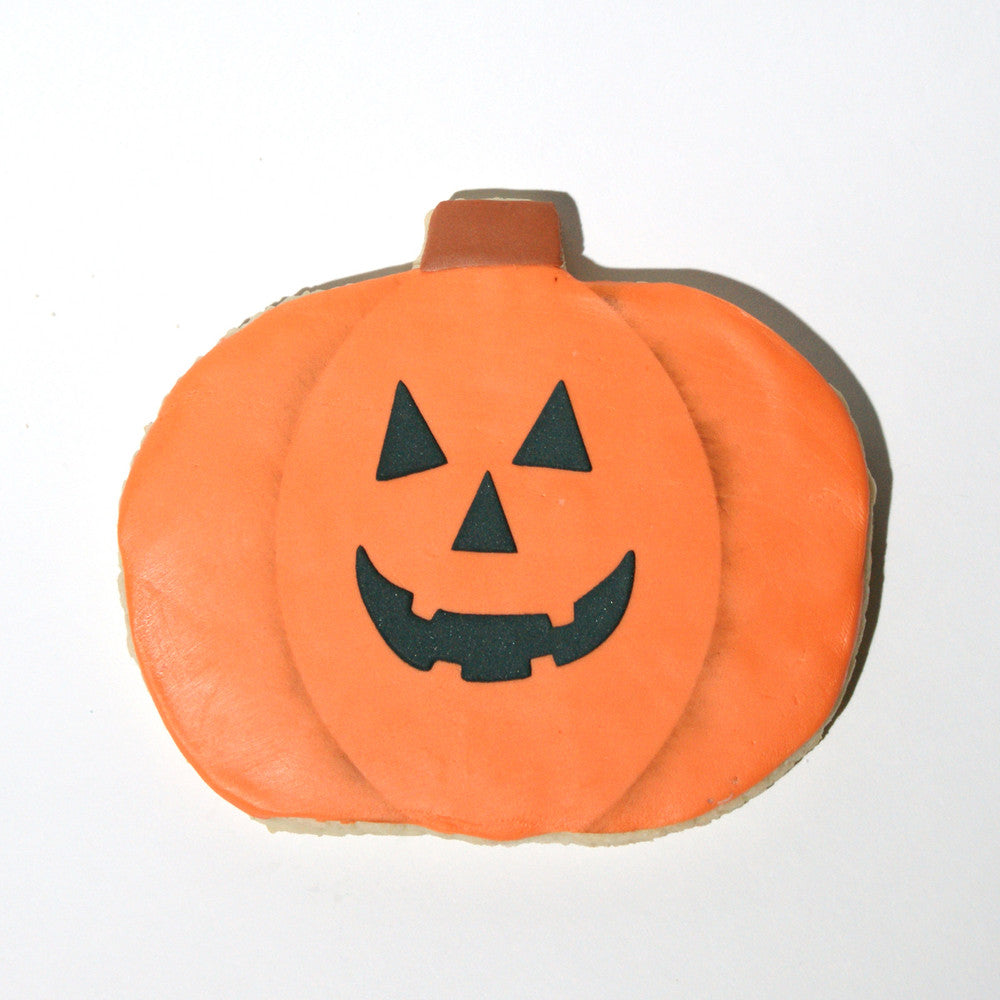 Jack-O-Lantern Halloween cookie with a smiling face, decorated using a pumpkin stencil for festive baking.