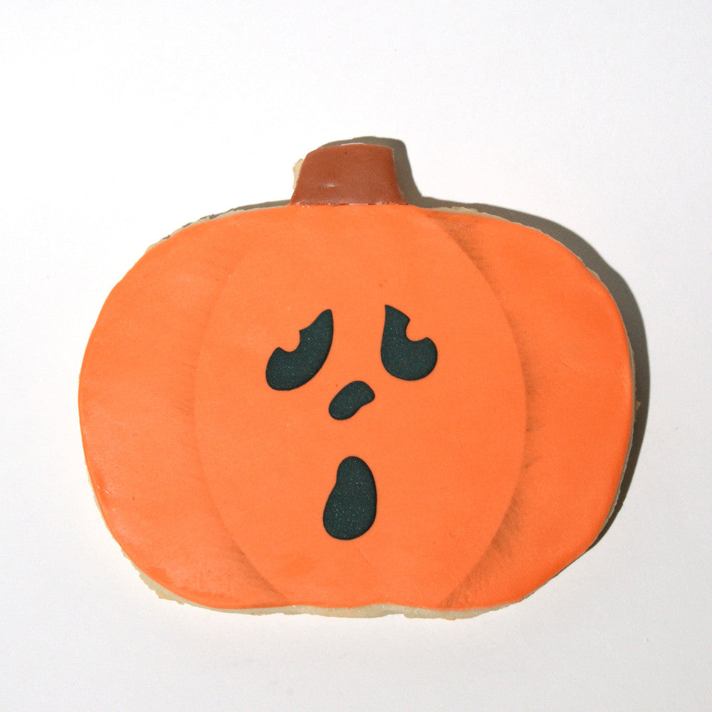 Orange pumpkin cookie decorated with a ghost face, perfect for Halloween celebrations.
