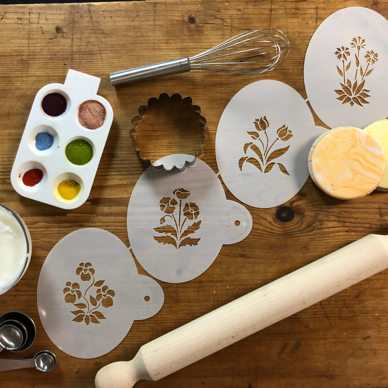 Spring Garden Cookie Stencil Set with flower designs, decorating tools, and a wooden rolling pin on a rustic table.