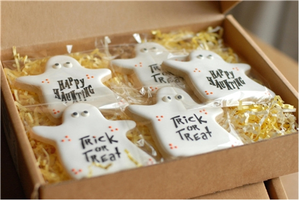 Ghost-shaped cookies with Halloween sayings 'Happy Haunting' and 'Trick or Treat' in festive packaging.