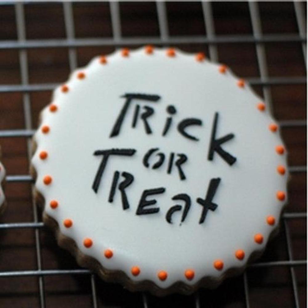 Halloween cookie with 'Trick or Treat' decoration, featuring orange accents and a round shape.