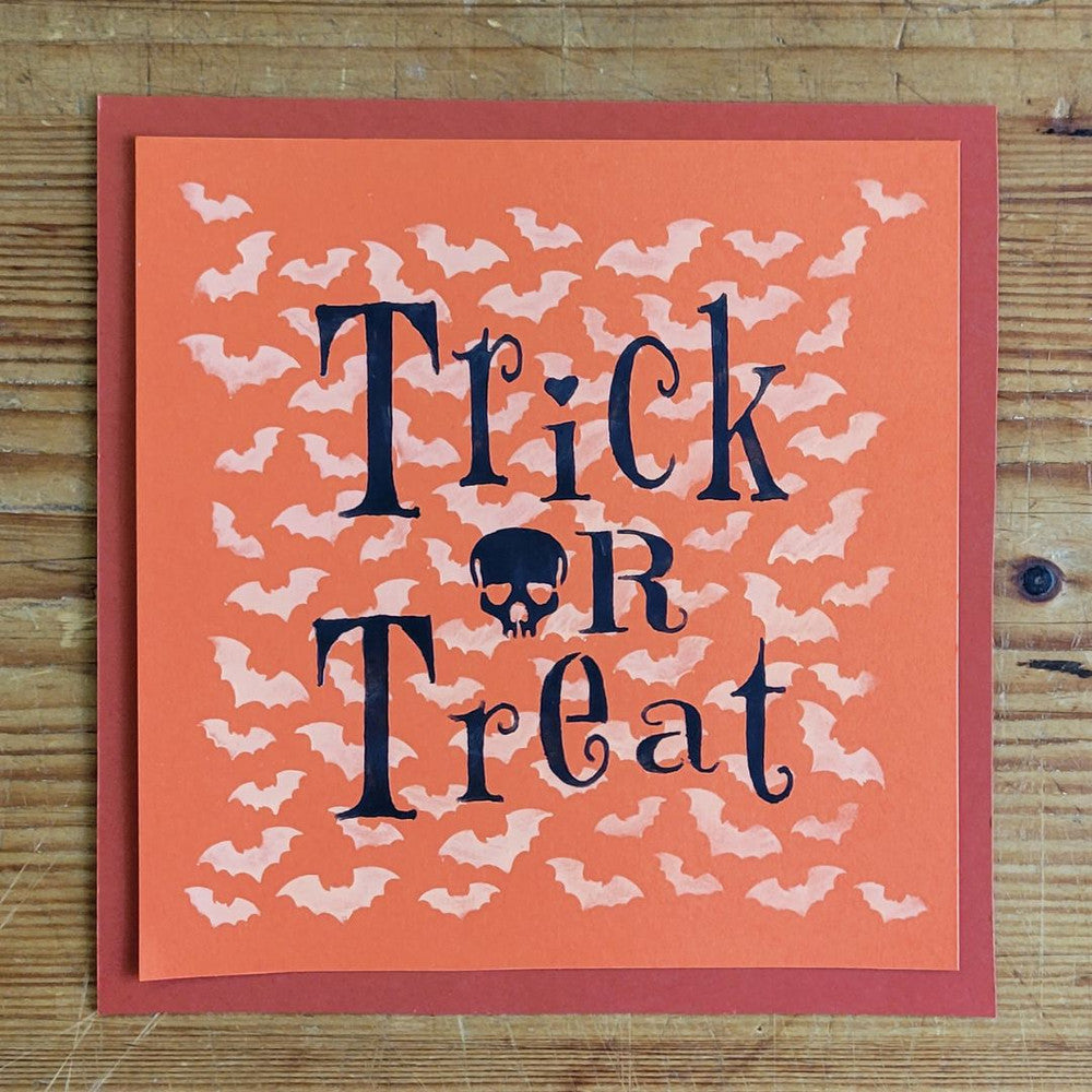 Orange Halloween card with 'Trick or Treat' text surrounded by scattered bats design.