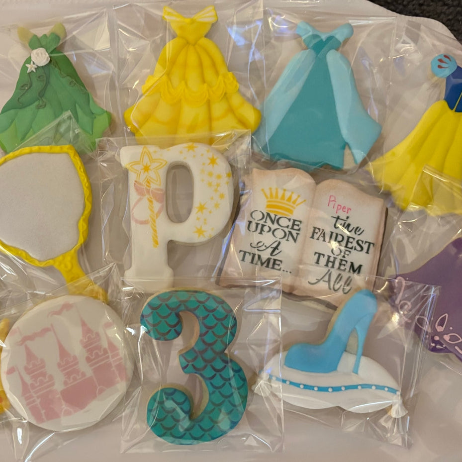 Decorative cookies shaped like dresses, numbers, and fairy tale elements on a clear background.