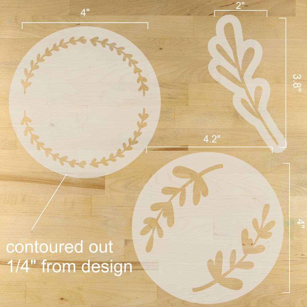 Decorative stencils with leaf patterns and measurements on a wooden surface