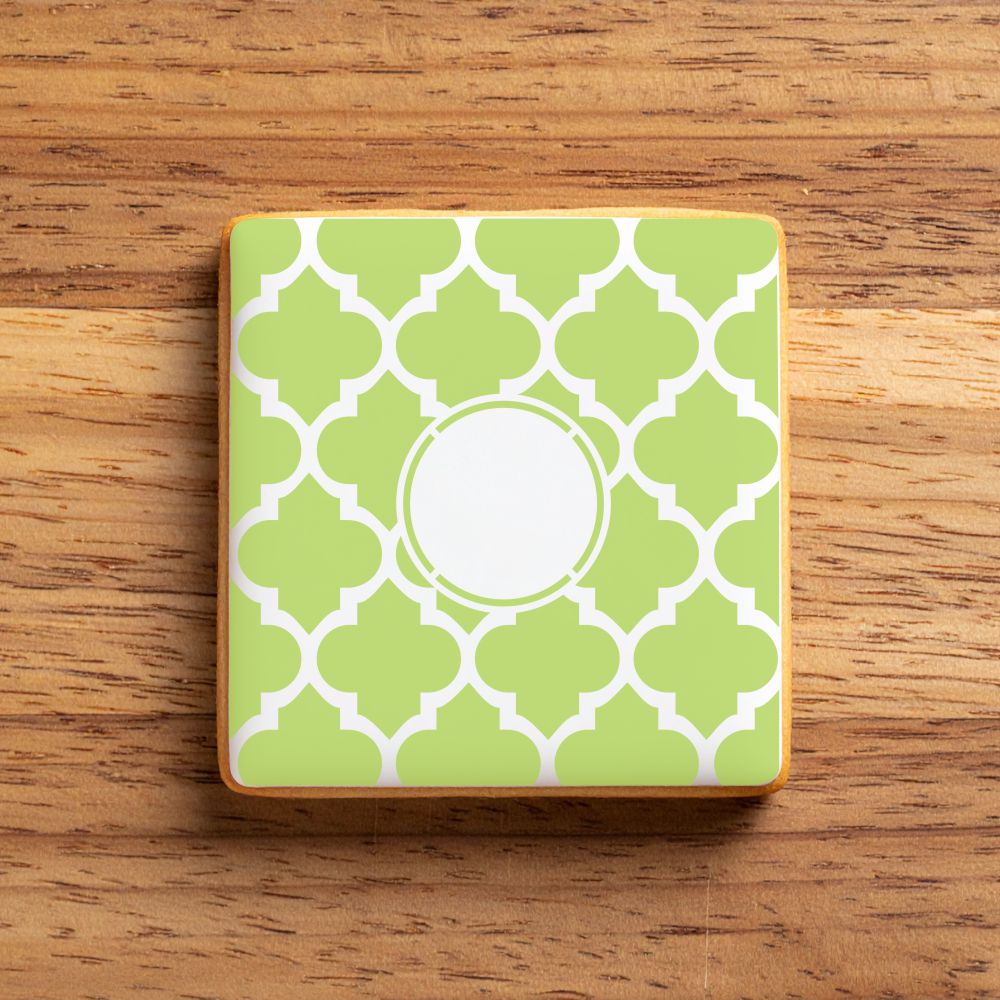 Green and white patterned stenciled onto a cookie on a wooden surface