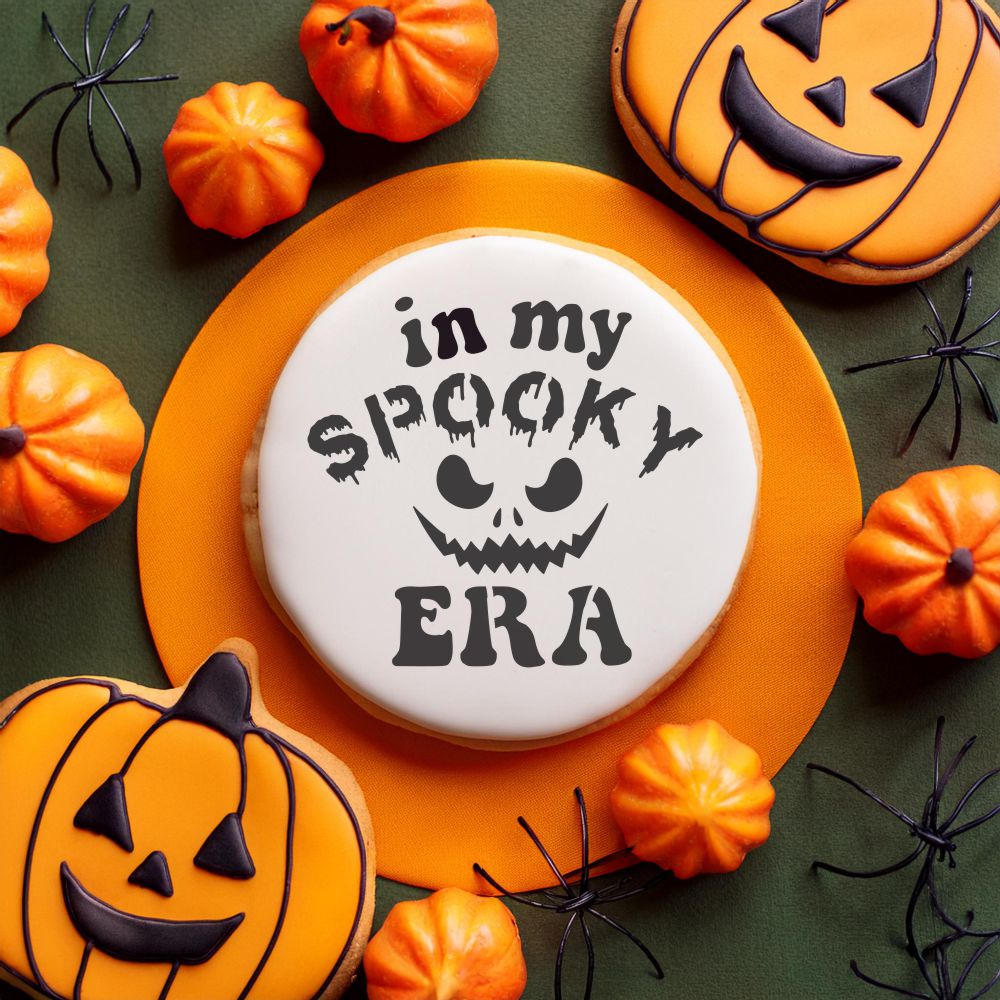 In My Spooky Era Halloween cookie stencil on a cookie surrounded by pumpkins and spiders, perfect for bakers this season.