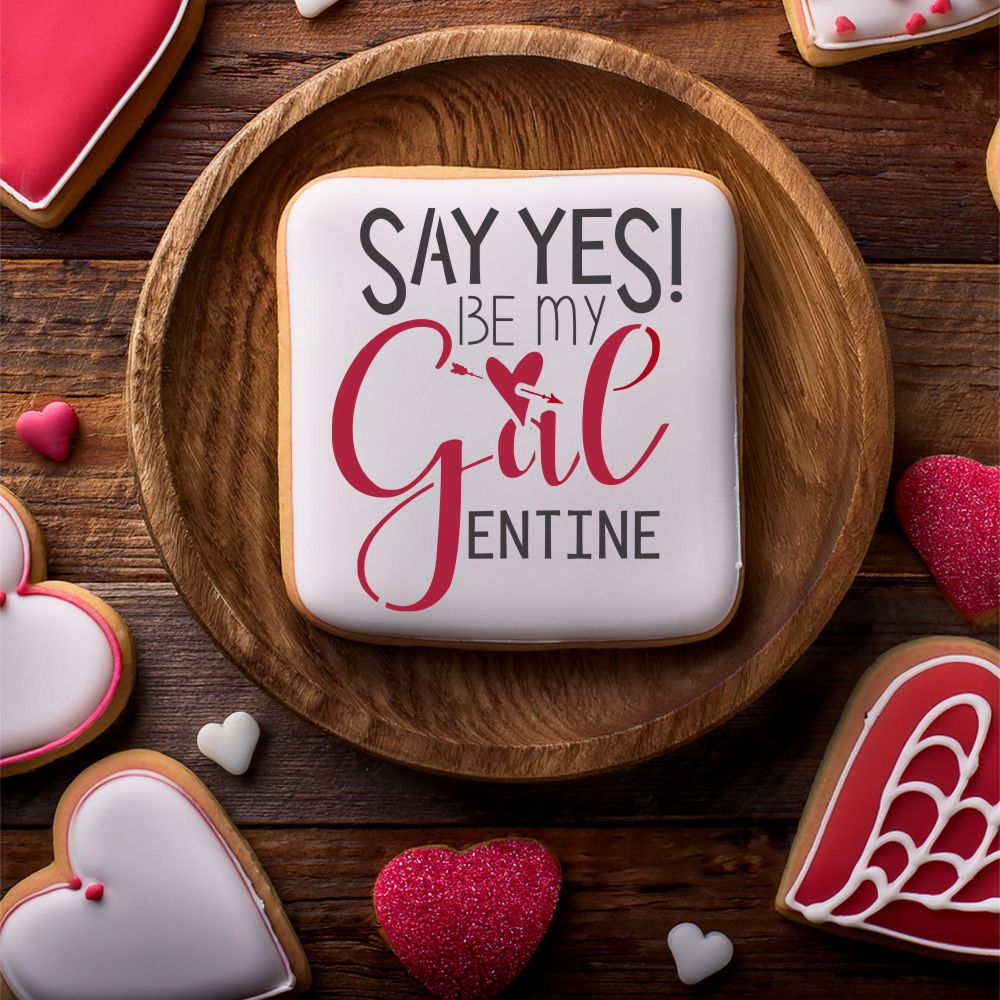Decorated cookie with the message 'Say Yes! Be My Galentine' on a wooden plate, perfect for Galentine's Day.
