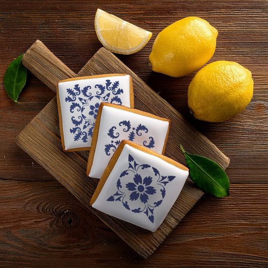 Decoratively iced cookies using a tile stencil, featuring Mediterranean designs on a wooden board with lemons.