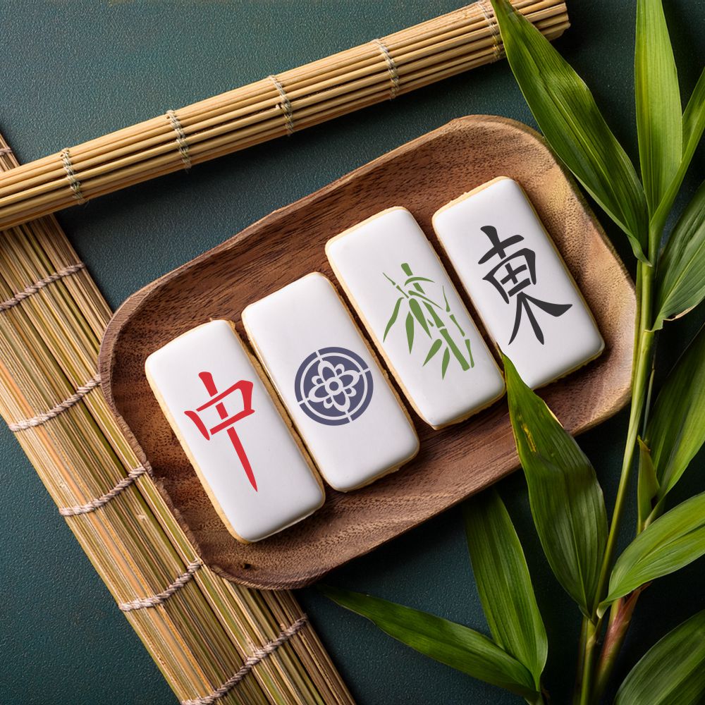 Mahjong tiles cookies artfully arranged on a wooden platter, showcasing unique designs with bamboo leaves.