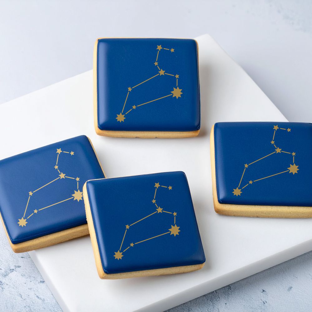 Cookies with blue icing and stenciled gold Leo star constellation.