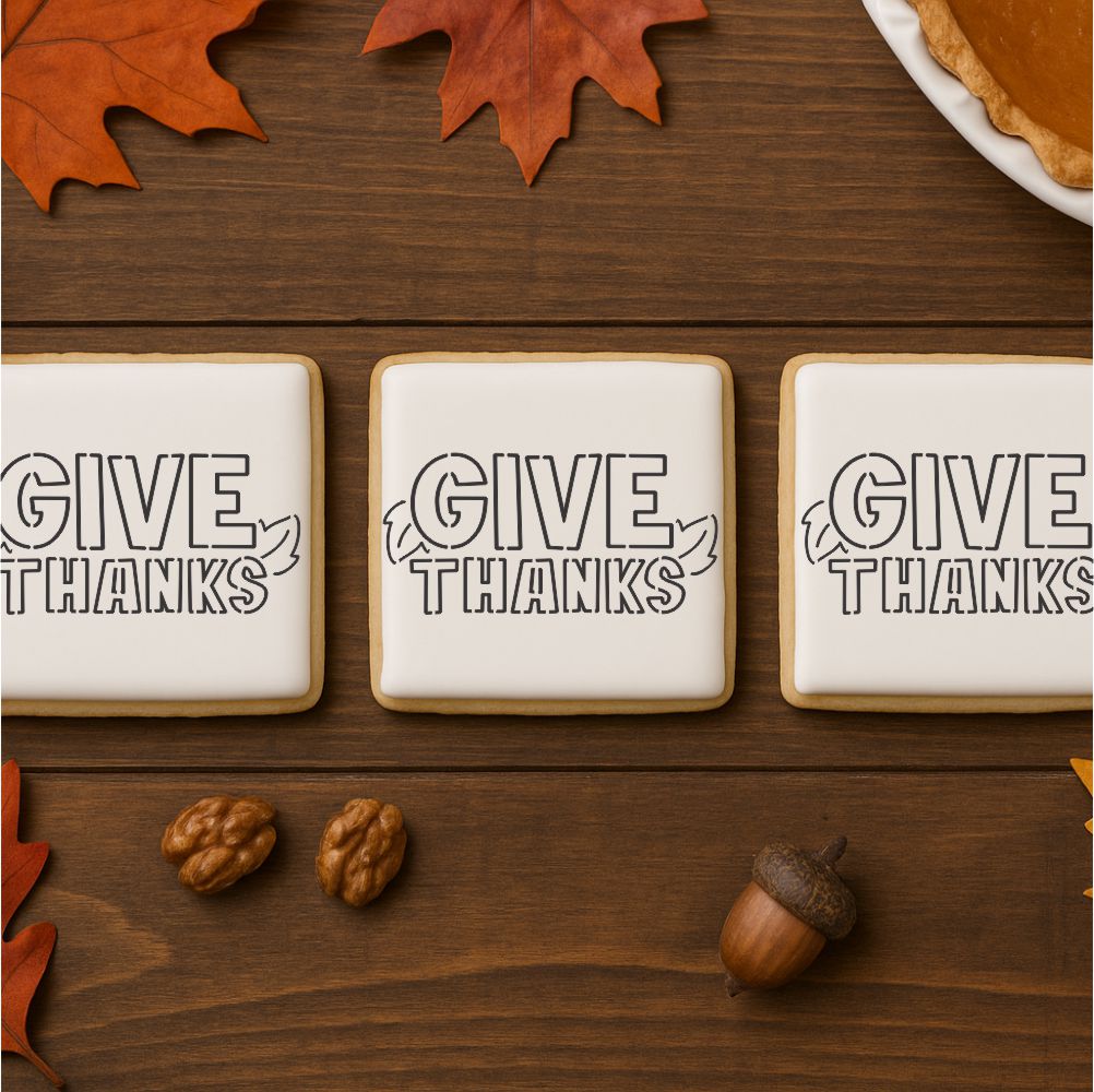 Three cookies with 'Give Thanks' text on a wooden surface with fall decorations.