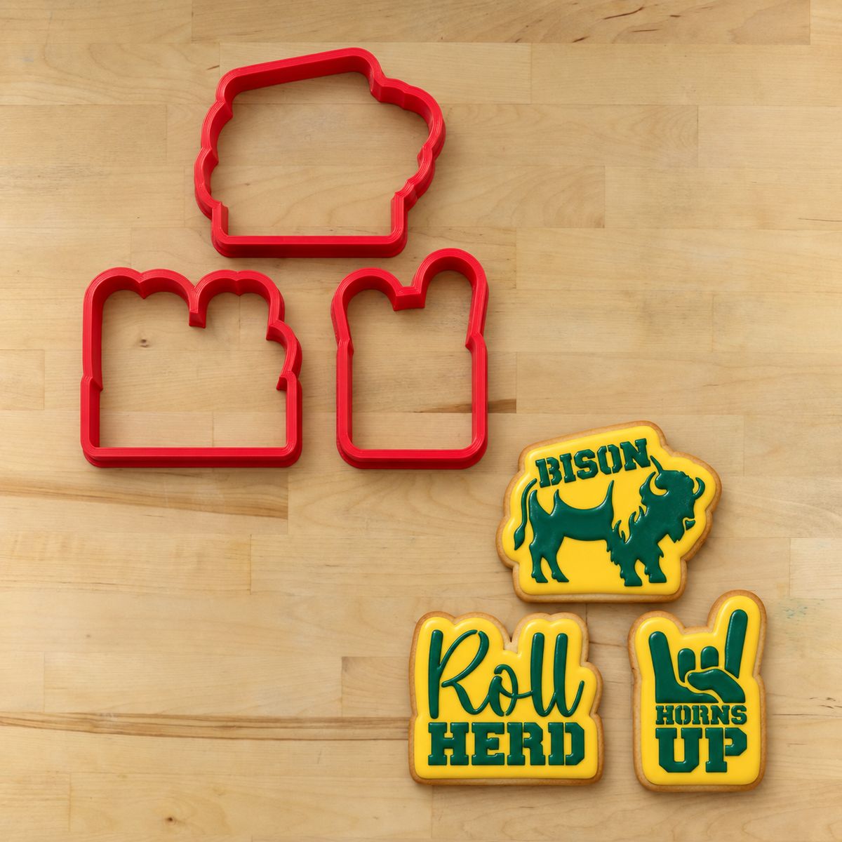 Roll Herd Cookie Cutters lying next to three flooded cookies stenciled with the Roll Herd Cookie Stencil Set.