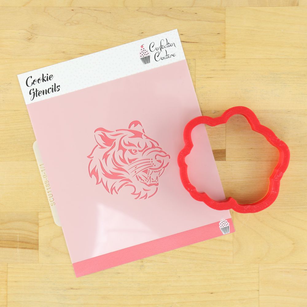 Tiger side view cookie stencil and red cookie cutter on a wooden surface.