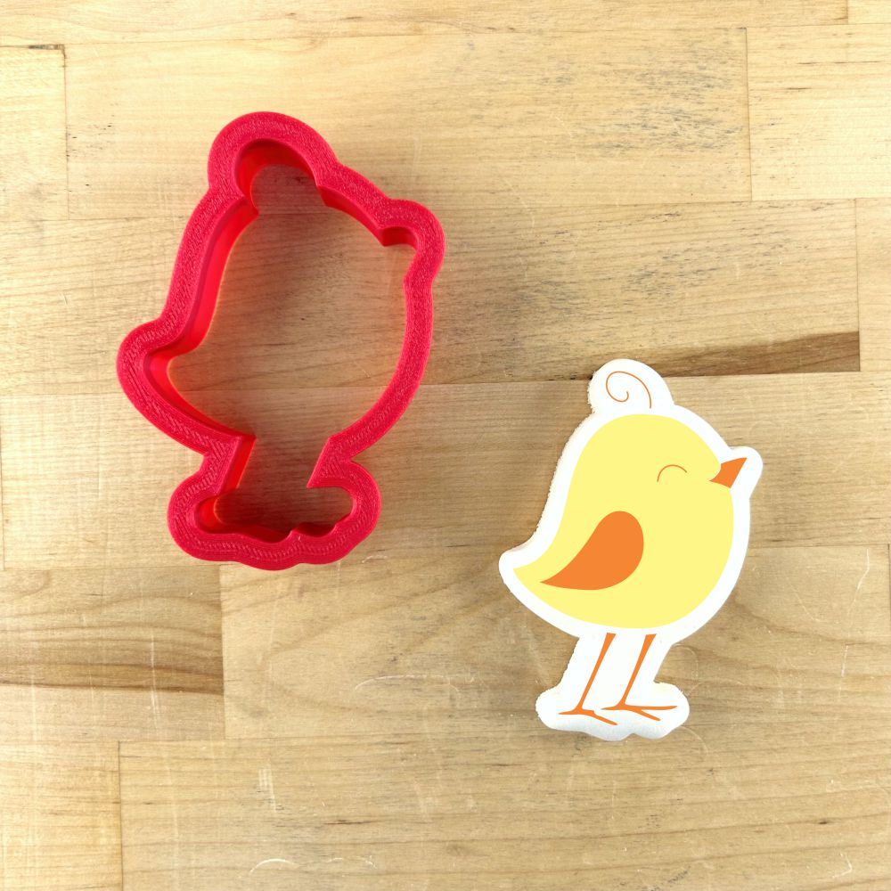 Easter Chick Cookie Stencil and matching cookie cutter in red and yellow on wooden background.