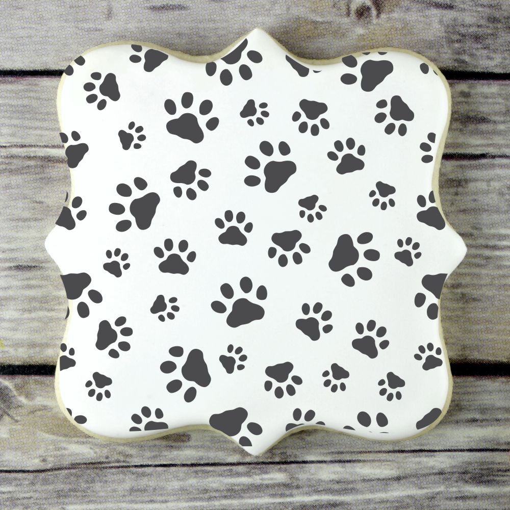 Mini dog paws cookie stencil featuring black paw prints on a white background, ideal for baking and decorating.