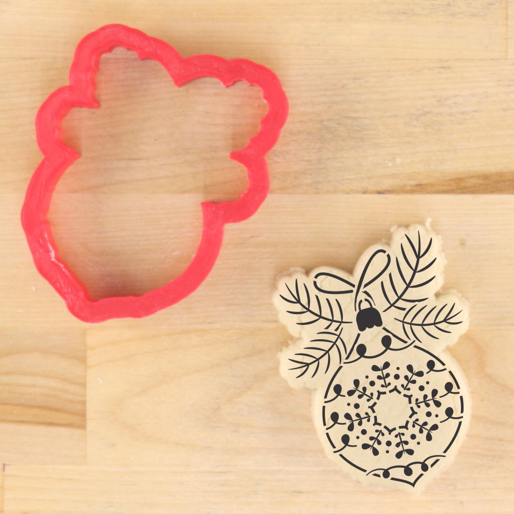 Vintage glass ornament cookie cutter and decorated cookie on a wooden surface, perfect for holiday projects.