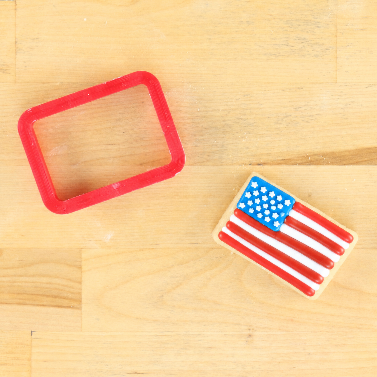 American flag cookie cutter and cookie that has been piped with a USA Flag design