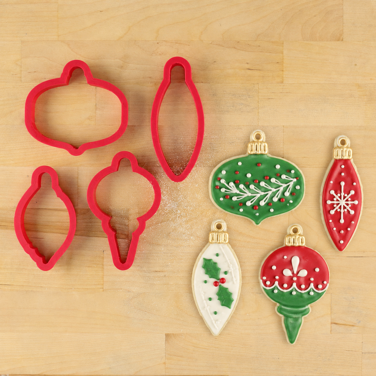 3D Printed Christmas Ornament Cookie Cutter Set, lying next to four Christmas ornament shaped cookies decorated for the holidays