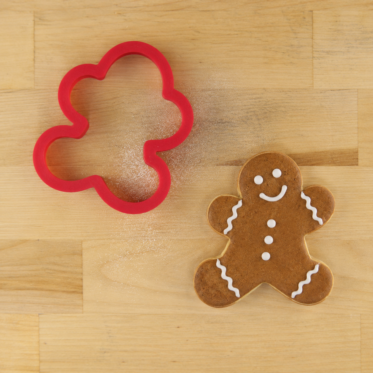 Gingerbread Man Cookie Cutter next to a Gingerbread man-shaped cookie decorated with brown icing and piped white icing