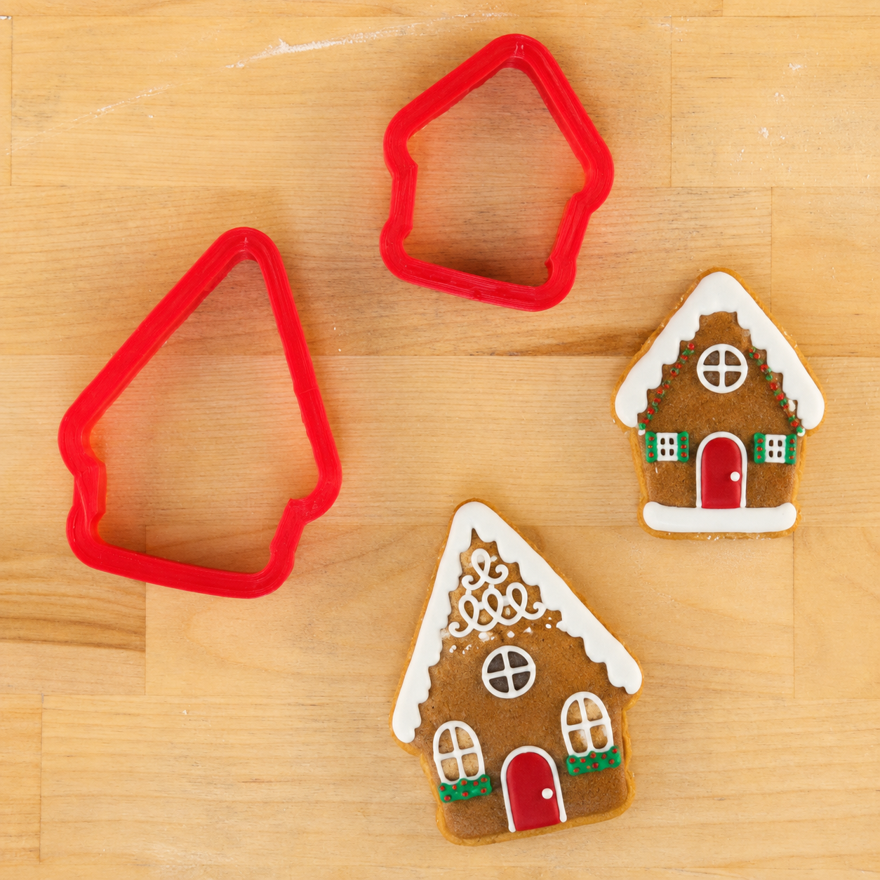Gingerbread House cookie cutters with gingerbread house-shaped cookies decorated for Christmas