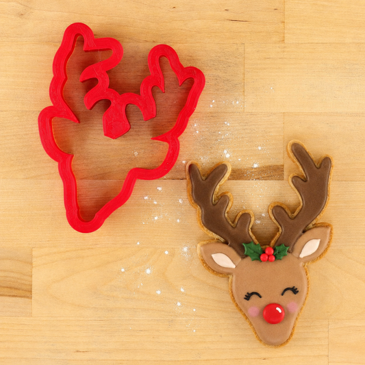 Reindeer Cookie Cutter next to a reindeer-shaped cookie decorated for Christmas