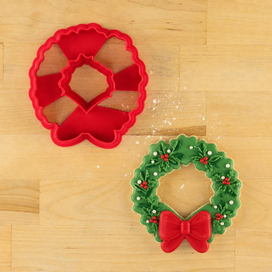 Wreath Christmas Cookie Cutter next to a Christmas wreath-shaped cookies decorated with green icing, edible decorations and a red bow.