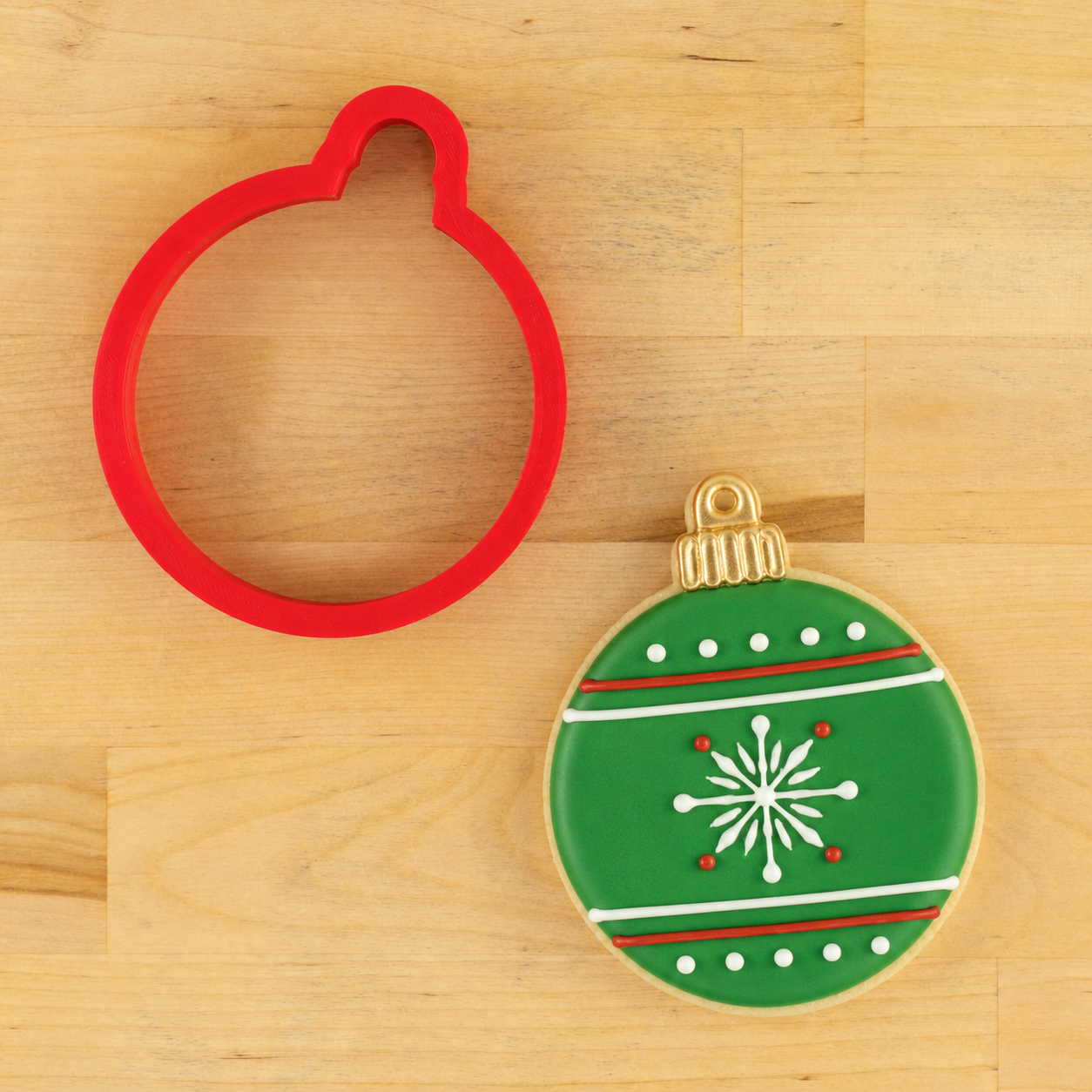 Round Christmas Ornament Cookie Cutter next to an ornament shaped cookie decorated for Christmas
