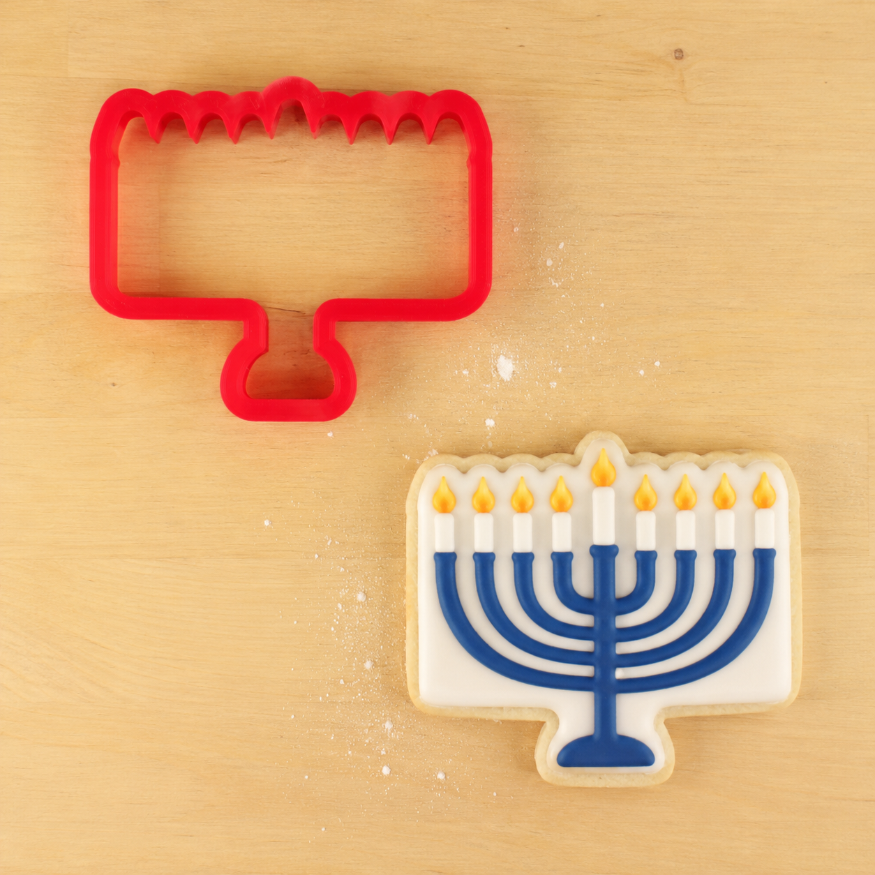 Menorah Cookie Cutter next to a Menorah-shaped cookie decorated for Hanukkah