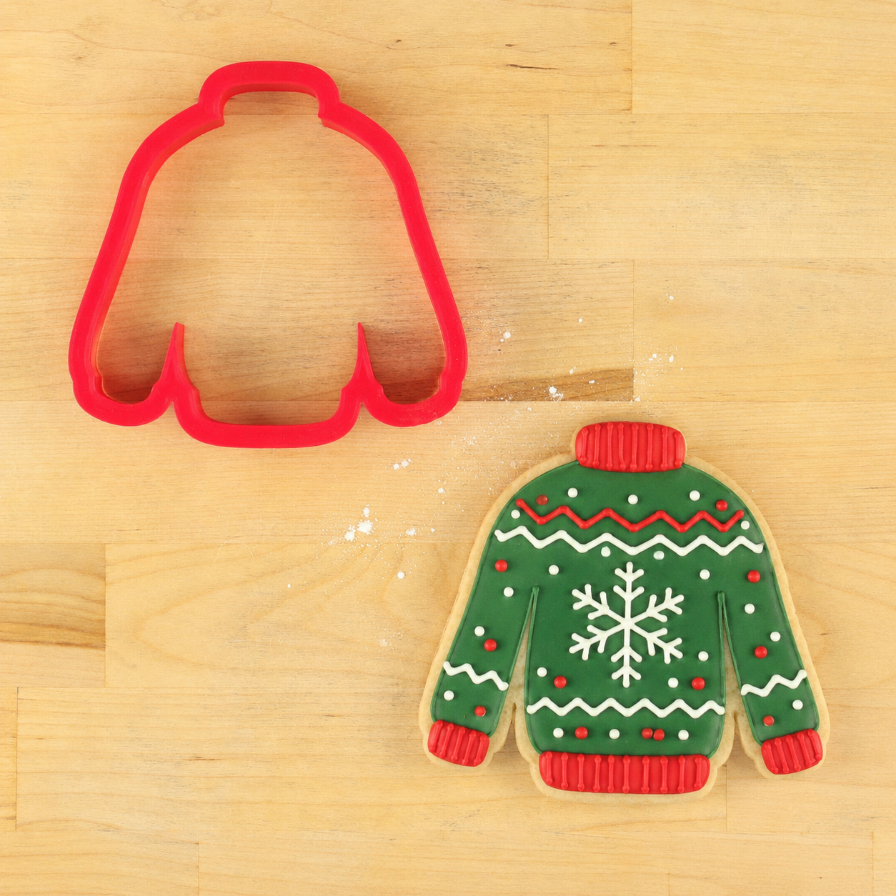 Sweater shaped cookie cutter and cookie decorated as a Christmas Sweater