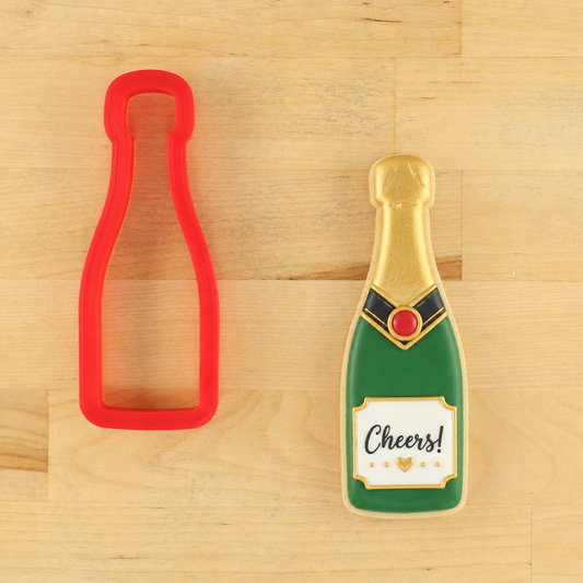 Champagne bottle cutter and champagne bottle shaped cookie that says "Cheers"