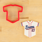 Cookie cutter shaped like a baseball jersey with 'Braves' and number '27' on a wooden surface.