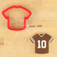 Sports jersey cookie cutter with decorated football jersey cookie featuring the number 10 on a wooden background.