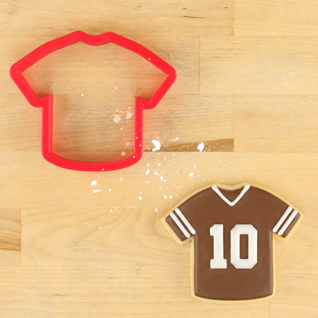 Sports jersey cookie cutter with decorated football jersey cookie featuring the number 10 on a wooden background.