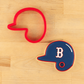 Blue cookie cutter shaped like a baseball helmet with a red outline on a wooden surface