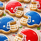 Cookies shaped like football helmets in red, blue, and white on a baking sheet.