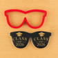 Sunglass shaped cookies iced black and stenciled with graduation cookie stencils