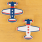 Two airplane-shaped cookies with red, white, and blue design on a wooden surface