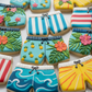 Decorative cookies shaped like swimsuit briefs with colorful designs on a white plate.