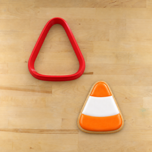 Candy Corn-shaped cookie cutter, next to a candy corn-shaped cookie flooded and piped with royal icing.
