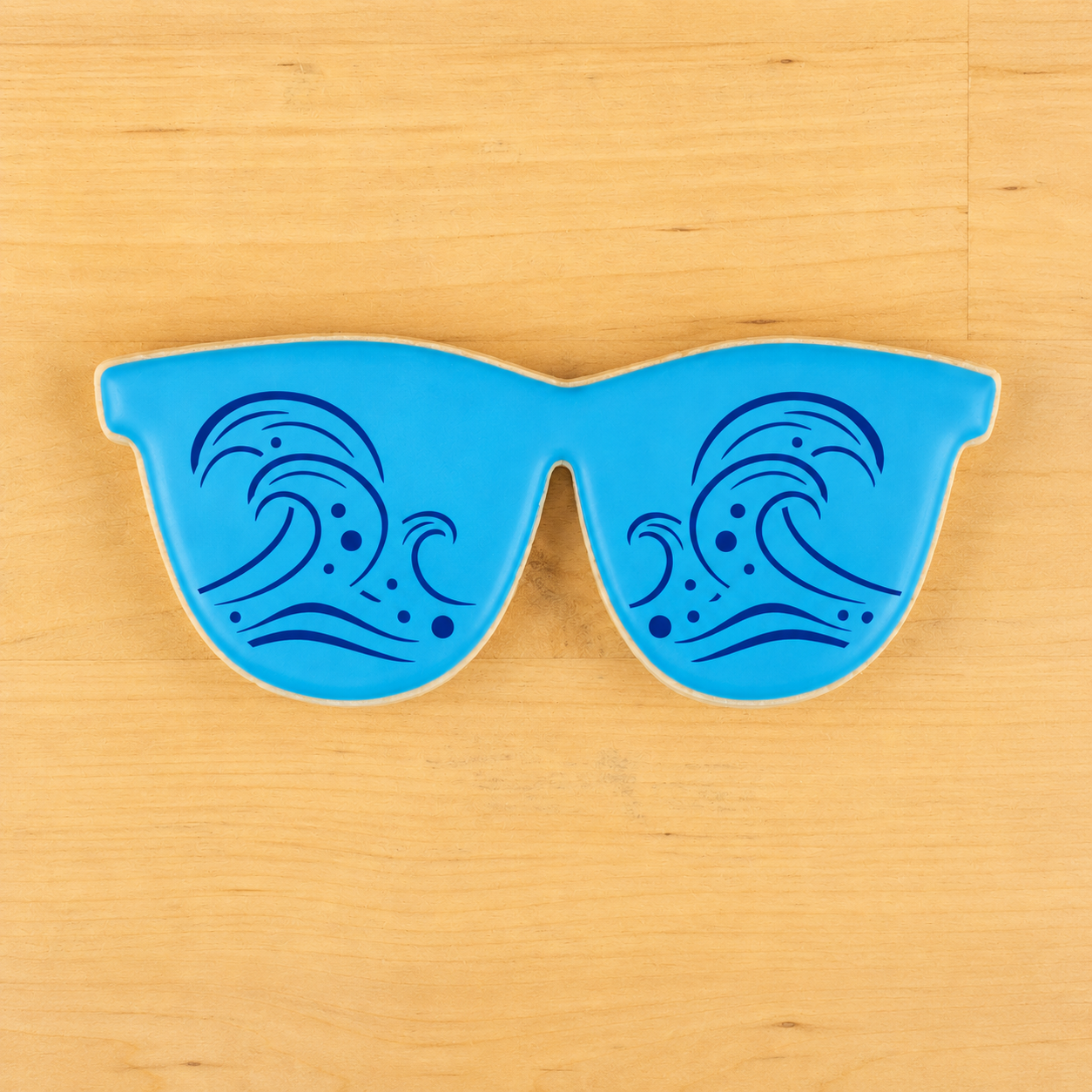 Sunglasses shaped cookie with ocean wave cookie stenciled applied to the the top