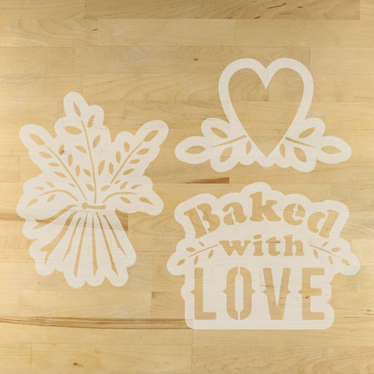 Three bread stencils on a wooden surface: a heart, a leaf, and 'Baked with Love'.
