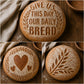 Three bread loaves with embossed designs on a wooden surface.