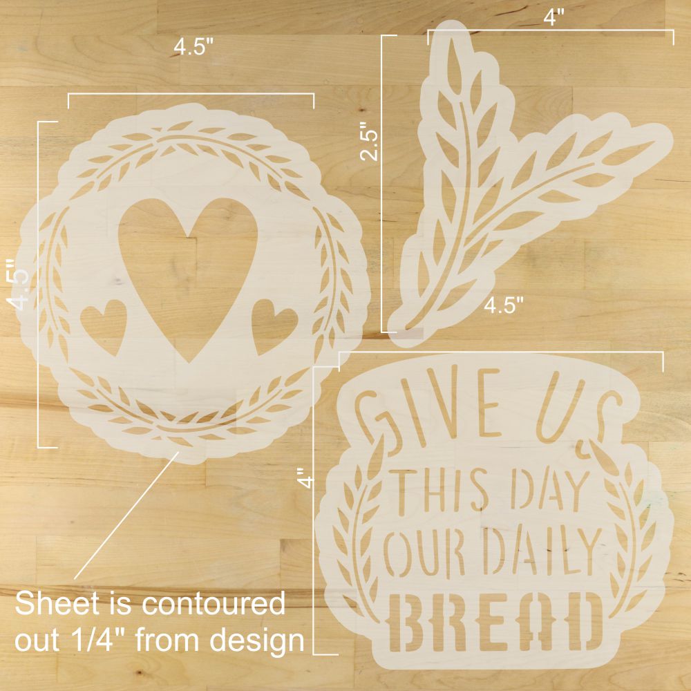 Decorative stencils with heart, leaf, and 'Give us this day our daily bread' design on a wooden surface.