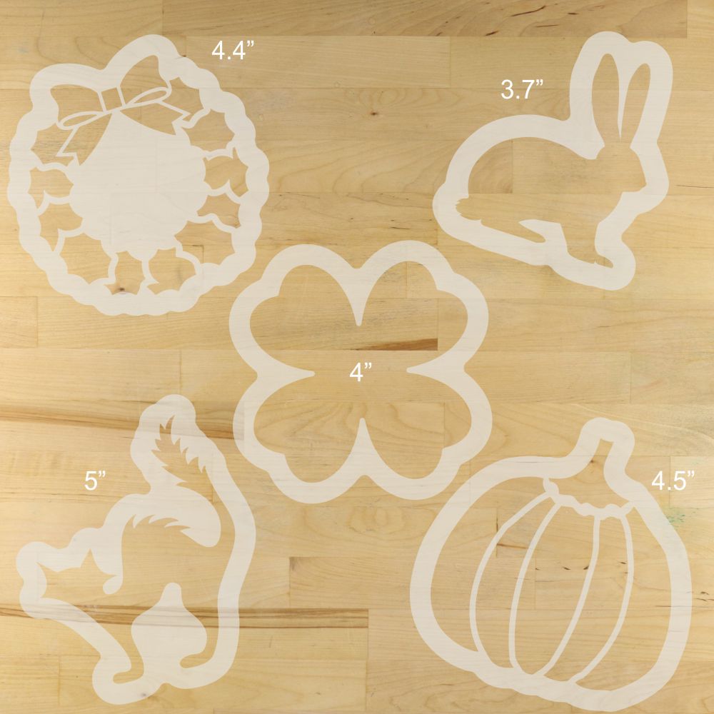 Set of reusable, holiday bread stencils with measurements on a wooden surface