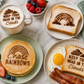 Breakfast setting with toast, pancakes, and eggs featuring motivational text.